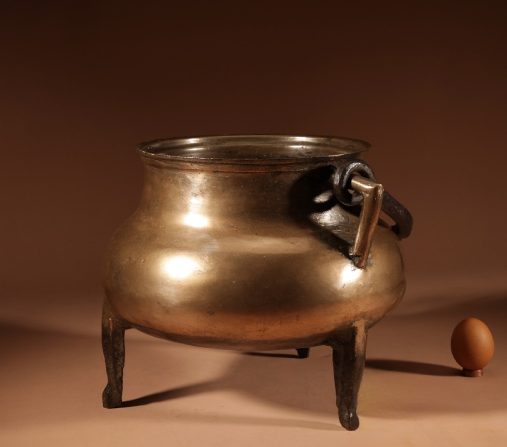 A 17th-century Continental bronze tripod cauldron featuring a bulbous body, three pointed feet, side handles, and a twisted wrought iron swing handle. View III