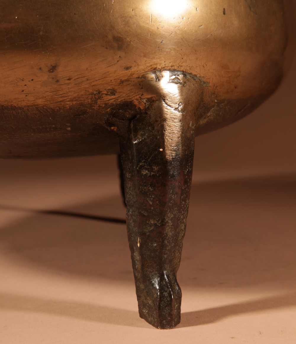 A 17th-century Continental bronze tripod cauldron featuring a bulbous body, three pointed feet, side handles, and a twisted wrought iron swing handle. View VIII