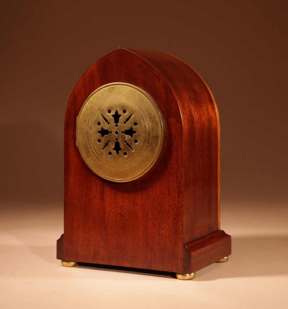 An Edwardian inlaid mahogany mantel clock with a lancet arch top, white enamel dial with Arabic numerals, and brass bun feet. View VII
