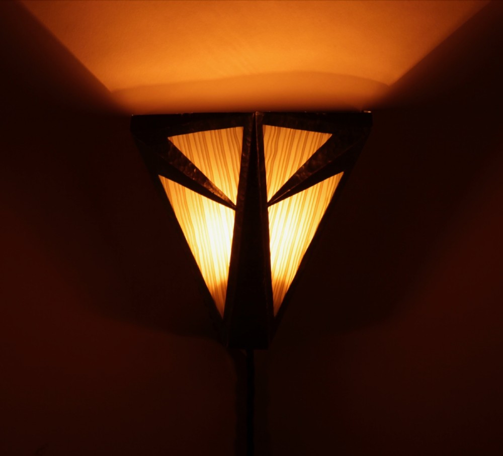 An Amsterdam School style triangular copper wall sconce featuring hand-chased geometric metalwork and pleated cream fabric panels. View II