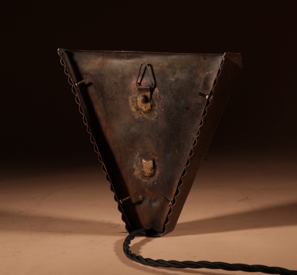 An Amsterdam School style triangular copper wall sconce featuring hand-chased geometric metalwork and pleated cream fabric panels. View VI