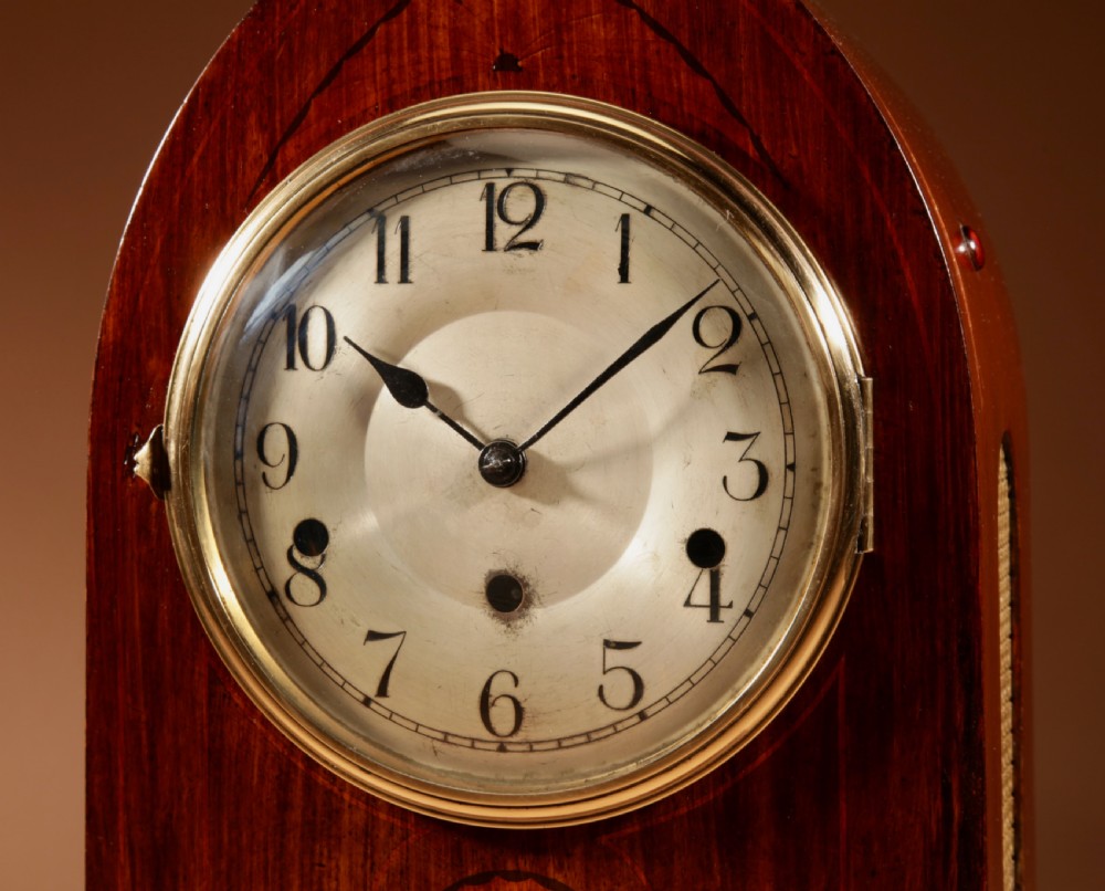 An Edwardian mahogany mantel clock featuring a pointed lancet arch top, oval marquetry inlay, and a circular white dial framed in brass. View II