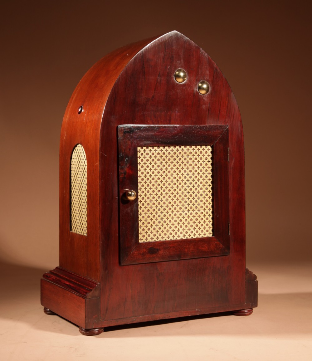 An Edwardian mahogany mantel clock featuring a pointed lancet arch top, oval marquetry inlay, and a circular white dial framed in brass. View V