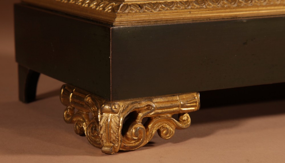 A late nineteenth-century French portico clock featuring dark patinated bronze columns, decorative gilt bronze mounts, a white enamel dial with Roman numerals, and an ornate pendulum. View IV