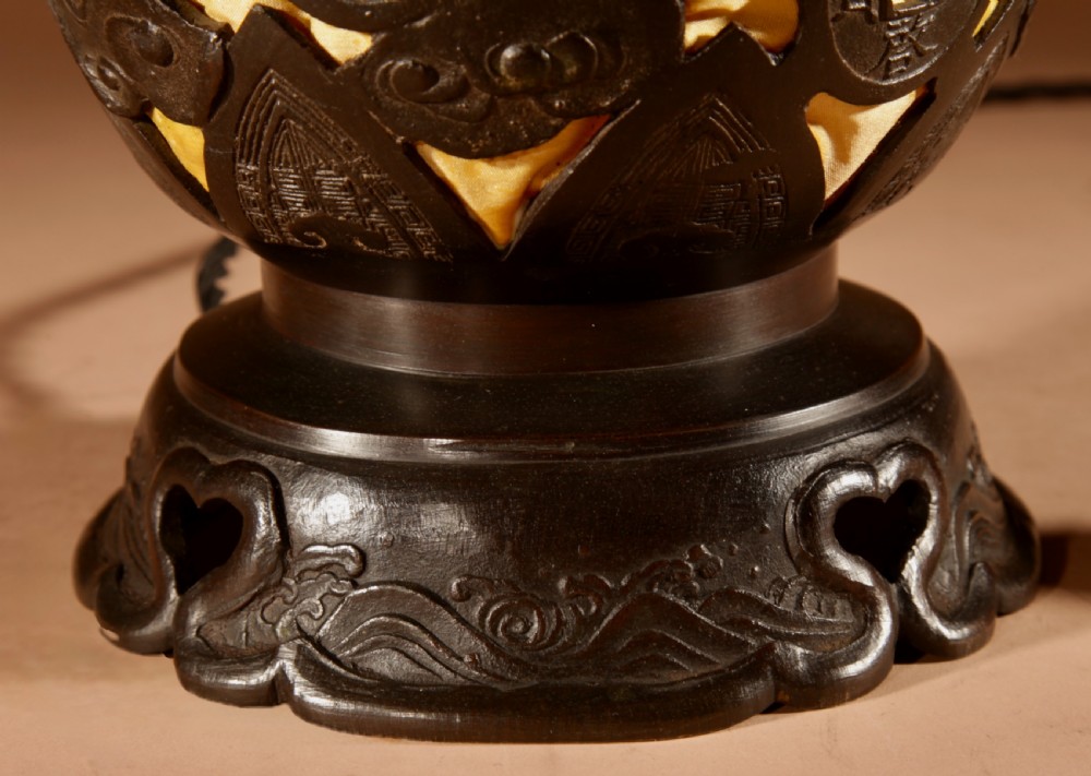 A dark bronze Japanese table lantern featuring reticulated coin and cloud pattern cut-outs, an illuminated amber interior, and a scalloped crest with a top handle. View IV
