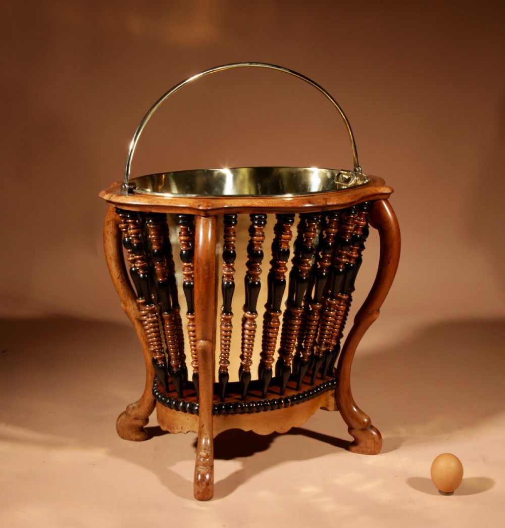 An oval Victorian walnut peat bucket featuring turned dual-tone spindles, four curved legs, and a swing-handled brass liner. View III
