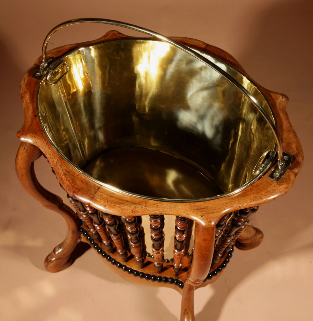 An oval Victorian walnut peat bucket featuring turned dual-tone spindles, four curved legs, and a swing-handled brass liner. View VIII