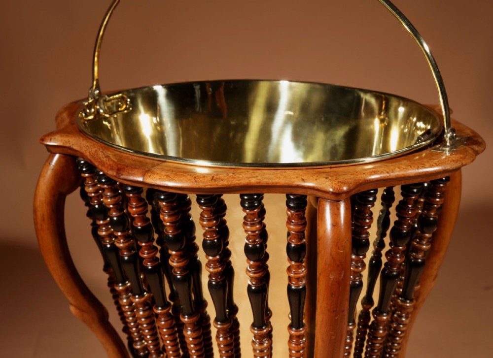 An oval Victorian walnut peat bucket featuring turned dual-tone spindles, four curved legs, and a swing-handled brass liner. View IX