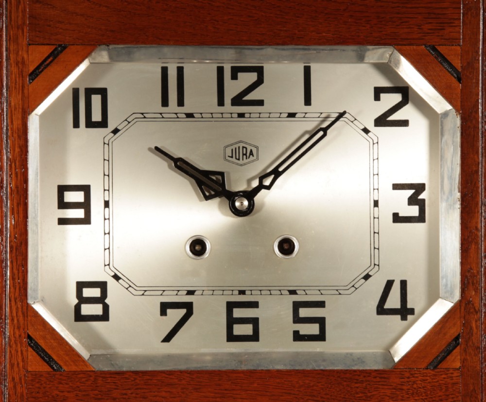 A rectangular Art Deco French oak wall clock featuring stylised side carvings, a silvered octagonal-framed dial face, and an etched lower glass window revealing a metal pendulum. View VI
