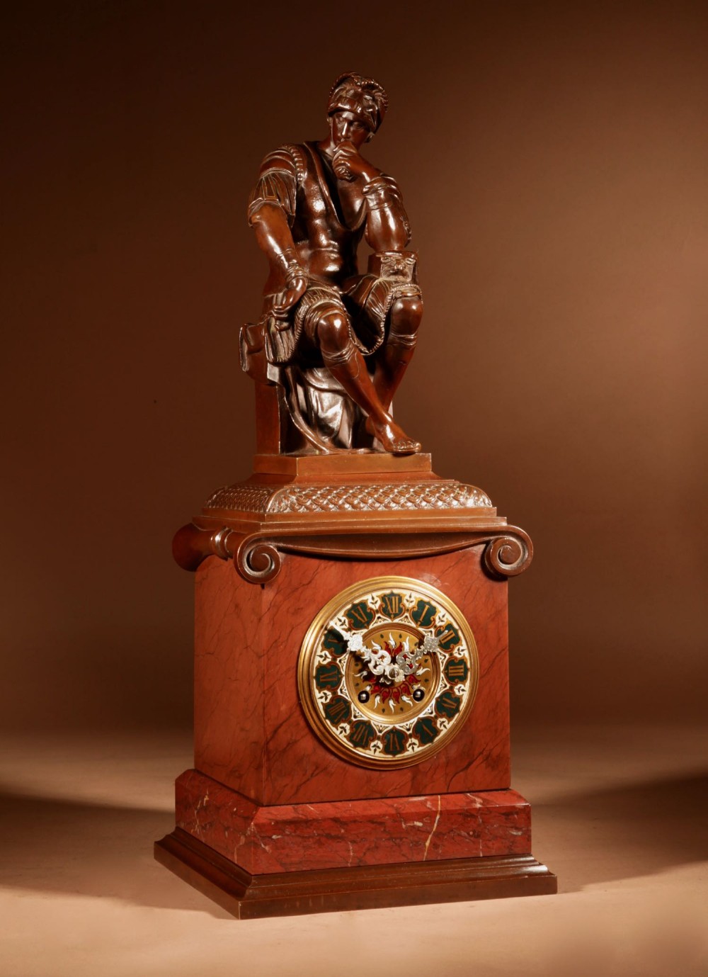 A 19th-century bronze and red marble mantel clock featuring a pensive classical male figure seated above an ornate circular dial.