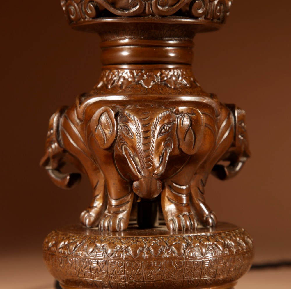 A dark patinated bronze table lamp featuring cast elephant and dragon motifs topped with a pleated conical lampshade. View VII