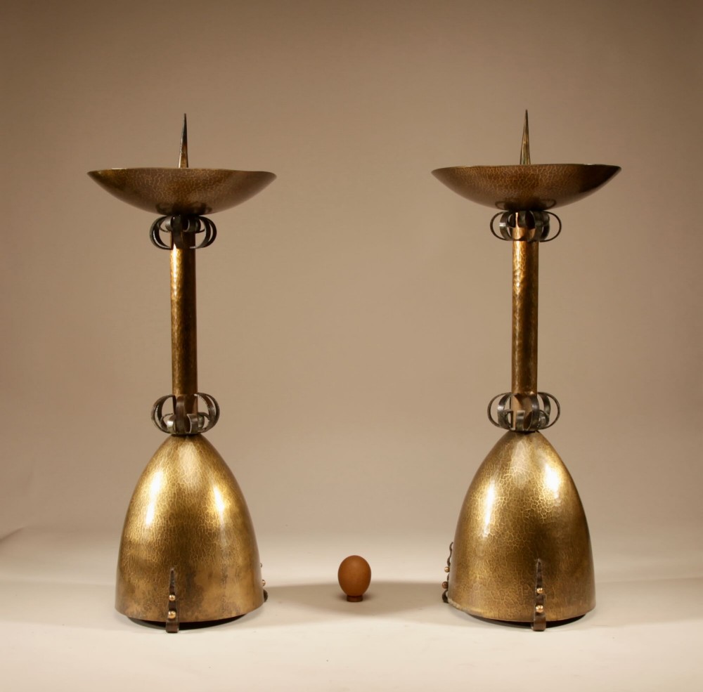 A pair of tall hand-hammered brass pricket candlesticks featuring domed bases, decorative wrought iron collars, and wide top dishes with central spikes.