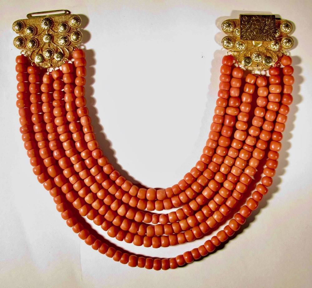 A six-strand natural red coral bead necklace featuring intricate gold filigree clasps decorated with beaded granulation at each end.