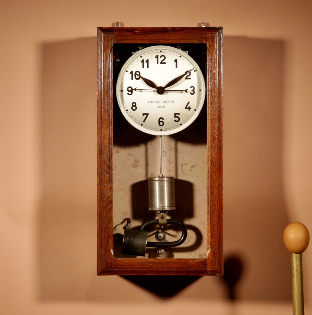 An Art Deco electric master clock set inside a glazed oak case with a white circular dial and visible pendulum mechanism.