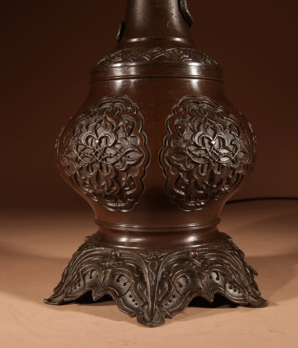 A dark patinated metal table lamp with relief dragon decoration, fitted with a pleated flared lampshade. View III
