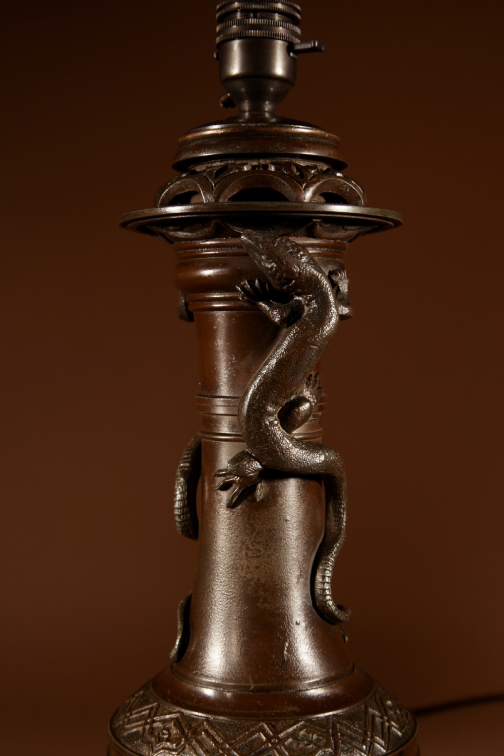 A dark patinated metal table lamp with relief dragon decoration, fitted with a pleated flared lampshade. View VII