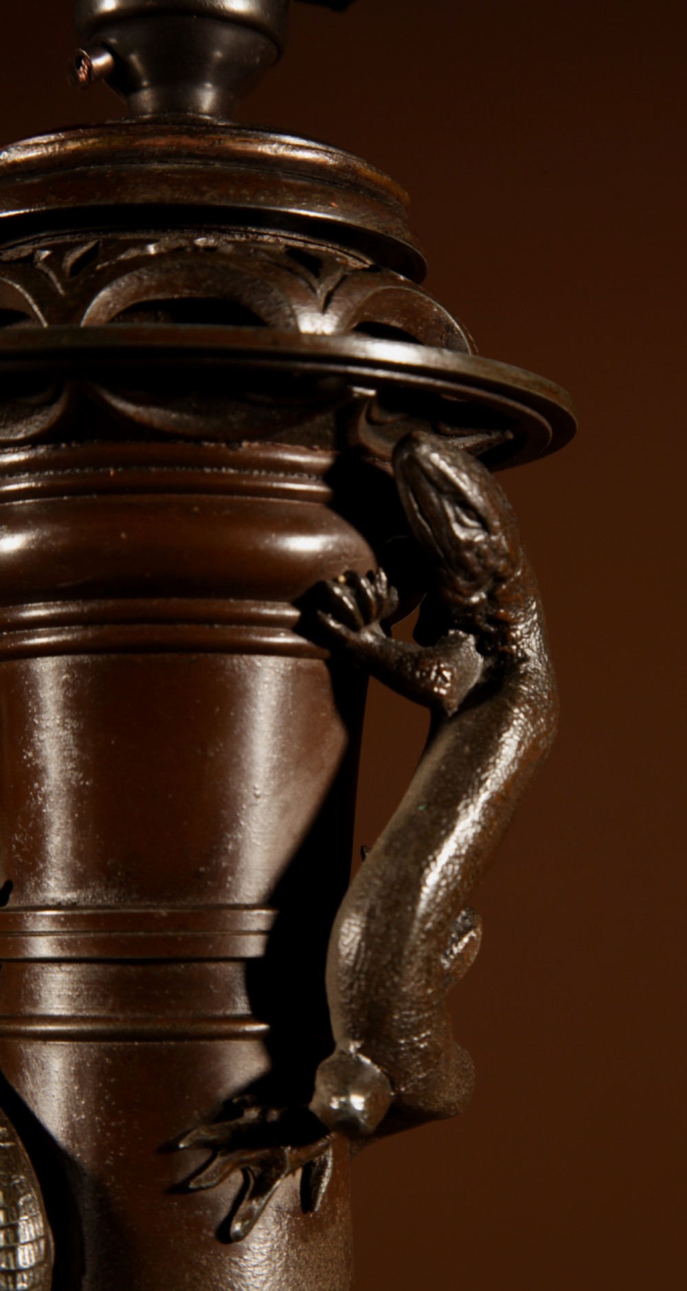 A dark patinated metal table lamp with relief dragon decoration, fitted with a pleated flared lampshade. View VIII
