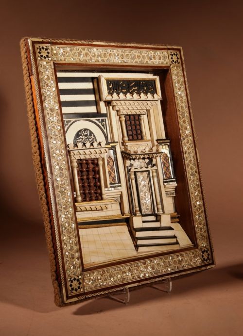 A framed three-dimensional wooden relief diorama depicting a Moorish building facade with intricate mother-of-pearl geometric inlay, miniature lattice windows, and Arabic calligraphy.