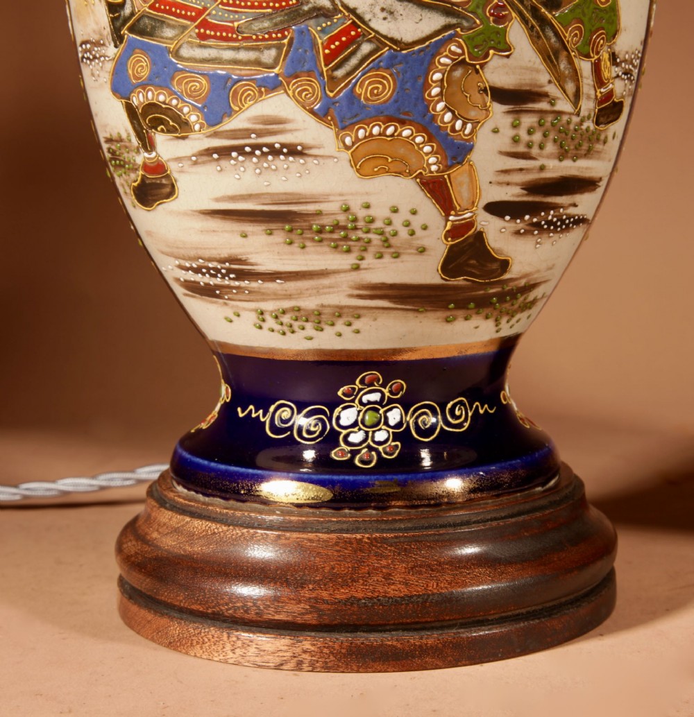 A pair of Japanese Satsuma ceramic table lamps featuring hand-painted figure scenes, cobalt blue accents, dark wooden bases, and cream pleated lampshades. View IV