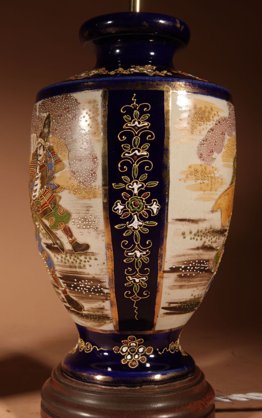 A pair of Japanese Satsuma ceramic table lamps featuring hand-painted figure scenes, cobalt blue accents, dark wooden bases, and cream pleated lampshades. View VIII