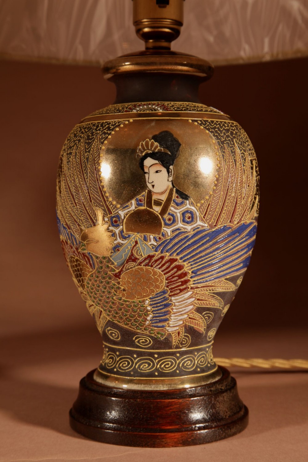 A pair of small Japanese Satsuma ceramic table lamps featuring figure paintings, gold gilding, dark wooden bases, and pleated cream shades. View III