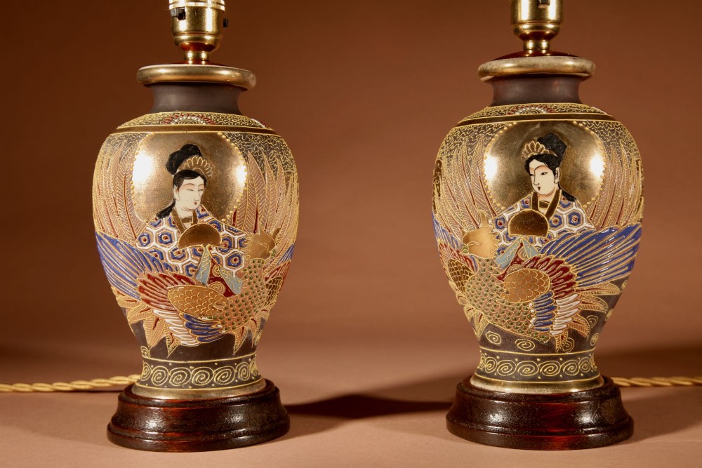 A pair of small Japanese Satsuma ceramic table lamps featuring figure paintings, gold gilding, dark wooden bases, and pleated cream shades. View VII