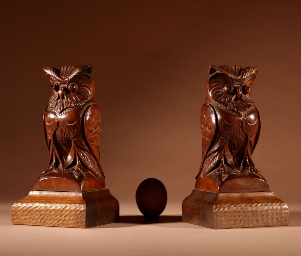 A pair of hand-carved dark wood owl figures with glass eyes mounted on carved wooden bases. View II