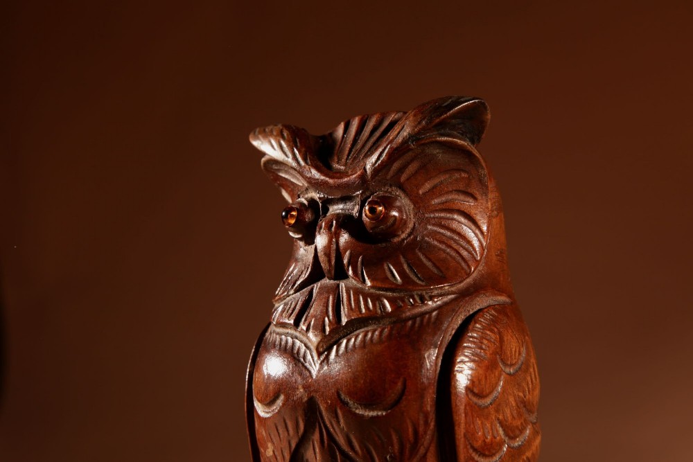 A pair of hand-carved dark wood owl figures with glass eyes mounted on carved wooden bases. View XIV