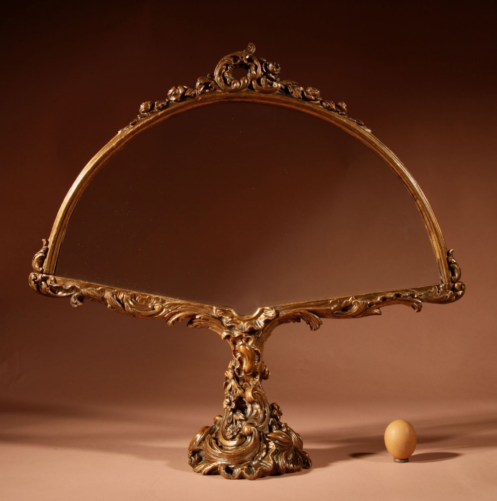 A fan-shaped glazed display case on an ornate Rococo style gilt metal pedestal base decorated with acanthus leaf scrollwork.