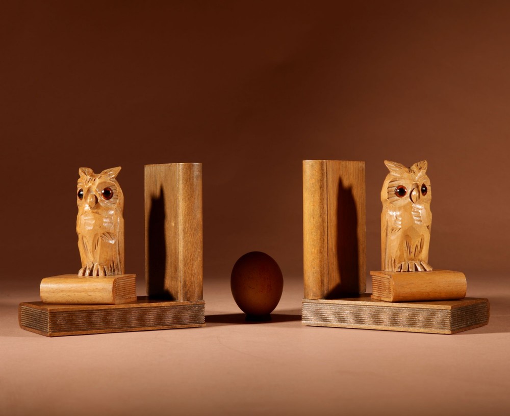 A pair of carved wooden owl bookends positioned on bases shaped like stacked books with amber glass eyes.
