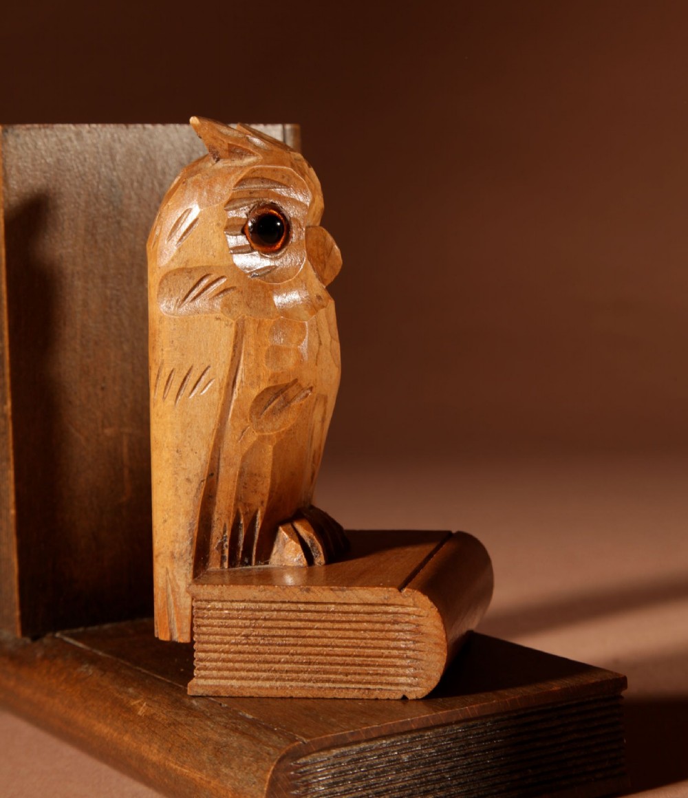 A pair of carved wooden owl bookends positioned on bases shaped like stacked books with amber glass eyes. View VII