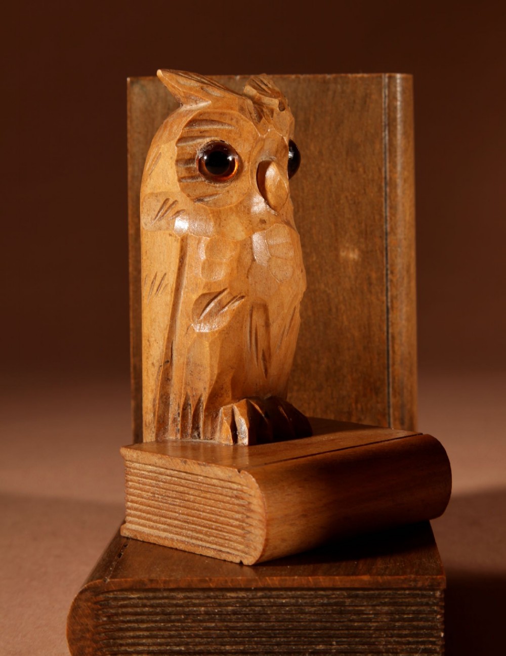 A pair of carved wooden owl bookends positioned on bases shaped like stacked books with amber glass eyes. View VIII