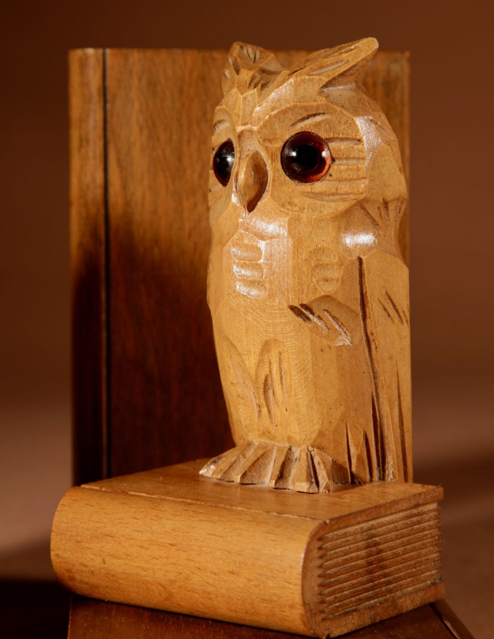 A pair of carved wooden owl bookends positioned on bases shaped like stacked books with amber glass eyes. View IX
