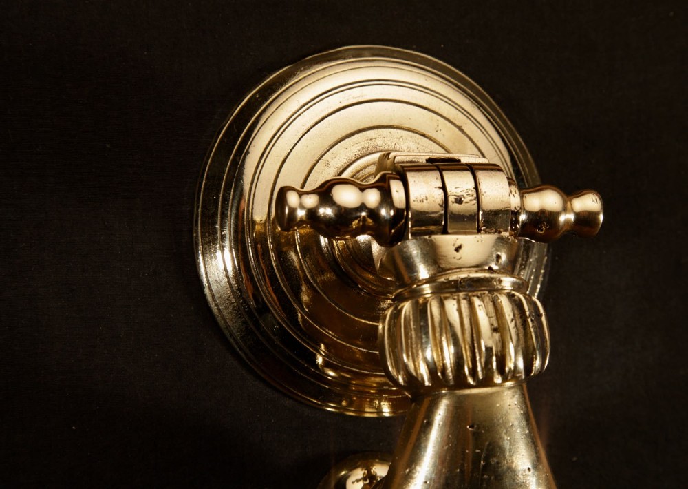 A cast bronze door knocker shaped as a hand holding a sphere, fitted to a circular stepped backplate. View V