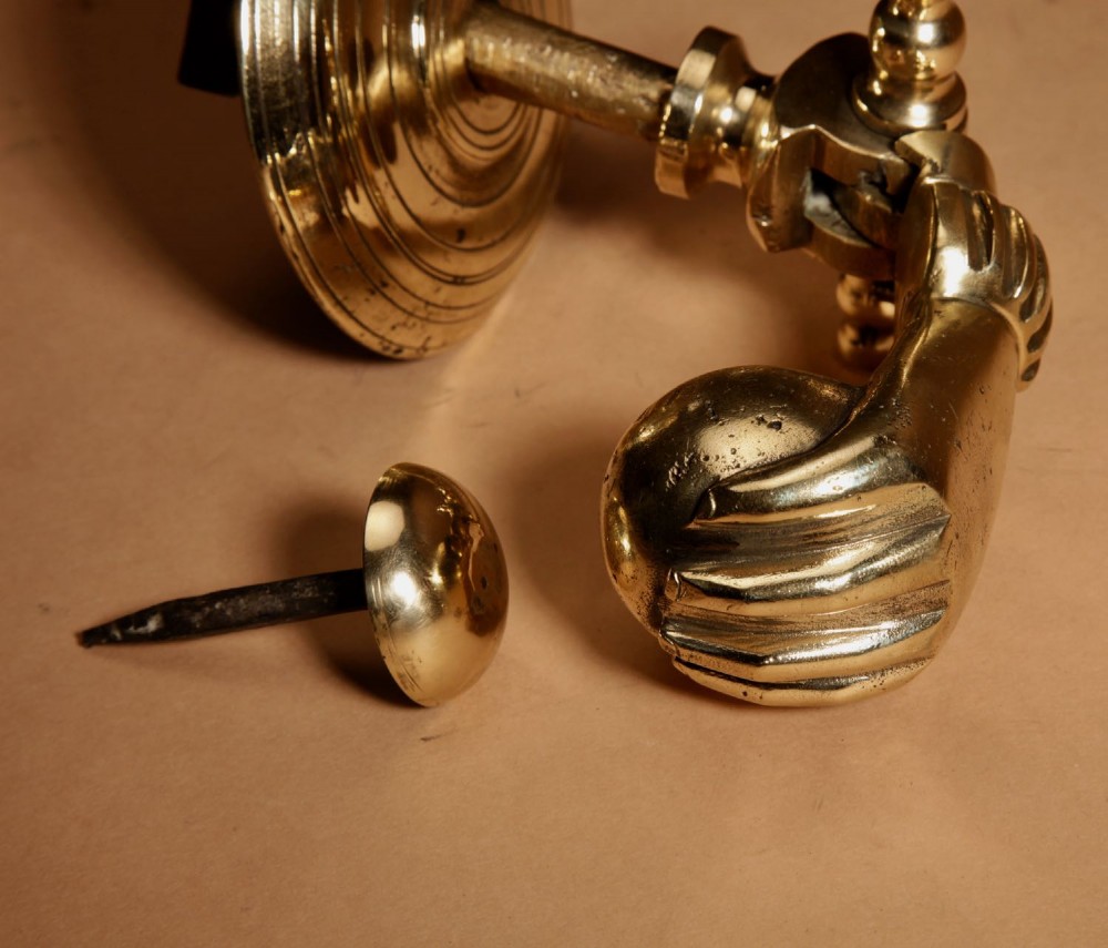 A cast bronze door knocker shaped as a hand holding a sphere, fitted to a circular stepped backplate. View IX