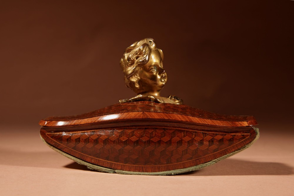 A nineteenth-century French rocker blotter featuring geometric wood parquetry inlay, a green felt underside, and a sculpted gilt bronze cherub head handle. View VI