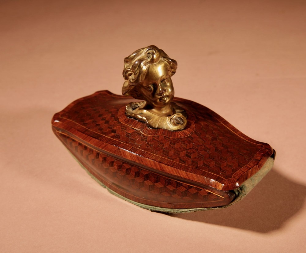 A nineteenth-century French rocker blotter featuring geometric wood parquetry inlay, a green felt underside, and a sculpted gilt bronze cherub head handle. View X