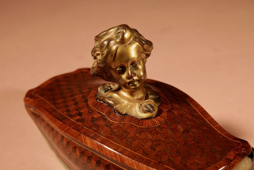 A nineteenth-century French rocker blotter featuring geometric wood parquetry inlay, a green felt underside, and a sculpted gilt bronze cherub head handle. View XI