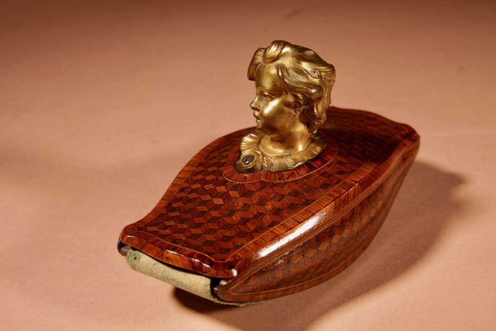 A nineteenth-century French rocker blotter featuring geometric wood parquetry inlay, a green felt underside, and a sculpted gilt bronze cherub head handle. View XII