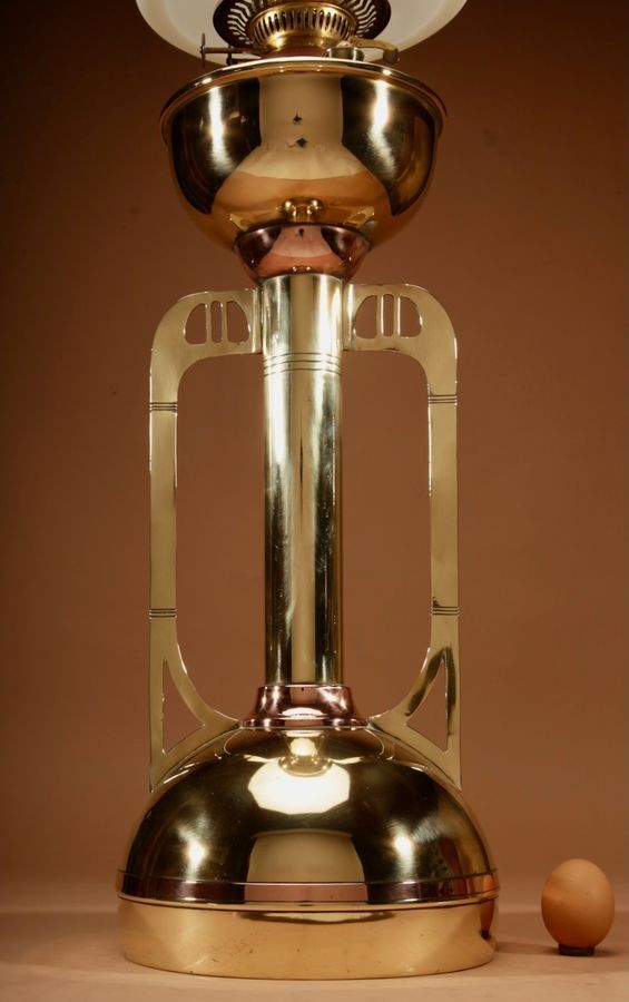 An antique Secessionist brass and copper paraffin table lamp featuring a white glass shade, central column body, and geometric side handles. View II