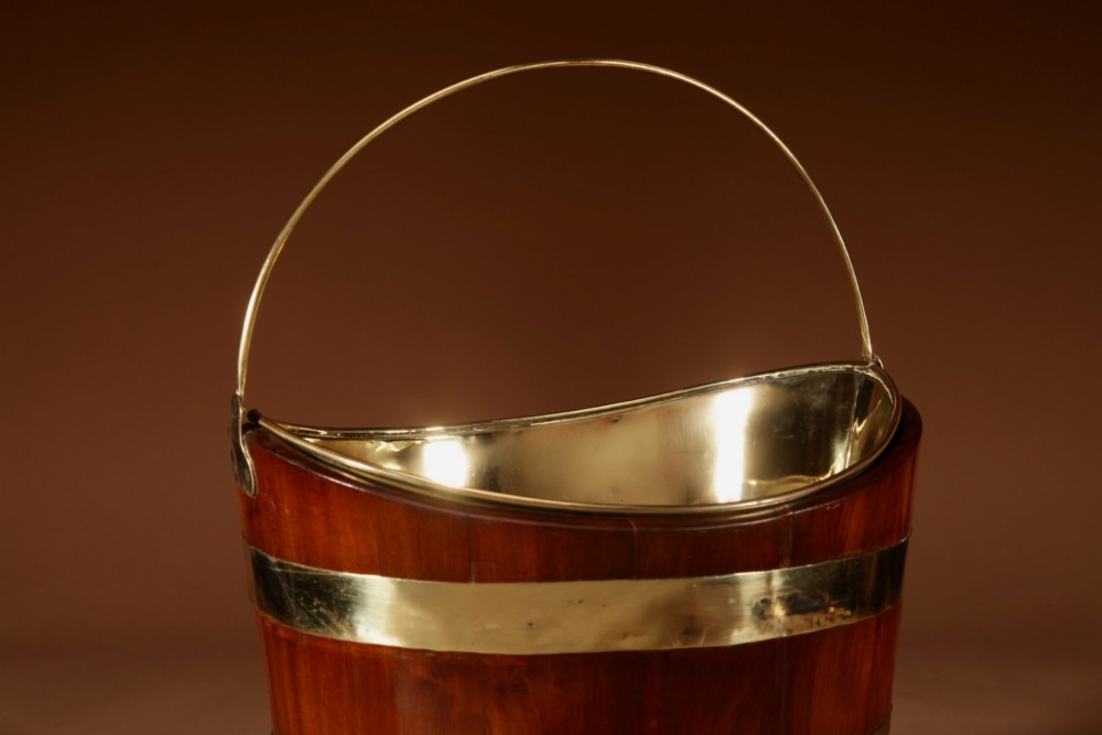 A boat-shaped mahogany peat bucket bound with polished brass bands and featuring a looped brass handle and removable brass liner. View IV