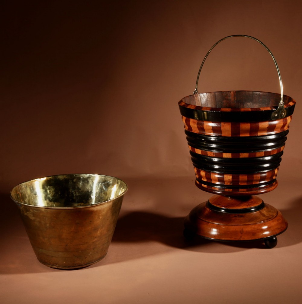 A Dutch coopered wooden peat bucket with alternating brown and ebonised staves, a brass swing handle, and a removable metal liner on a footed pedestal base. View VIII