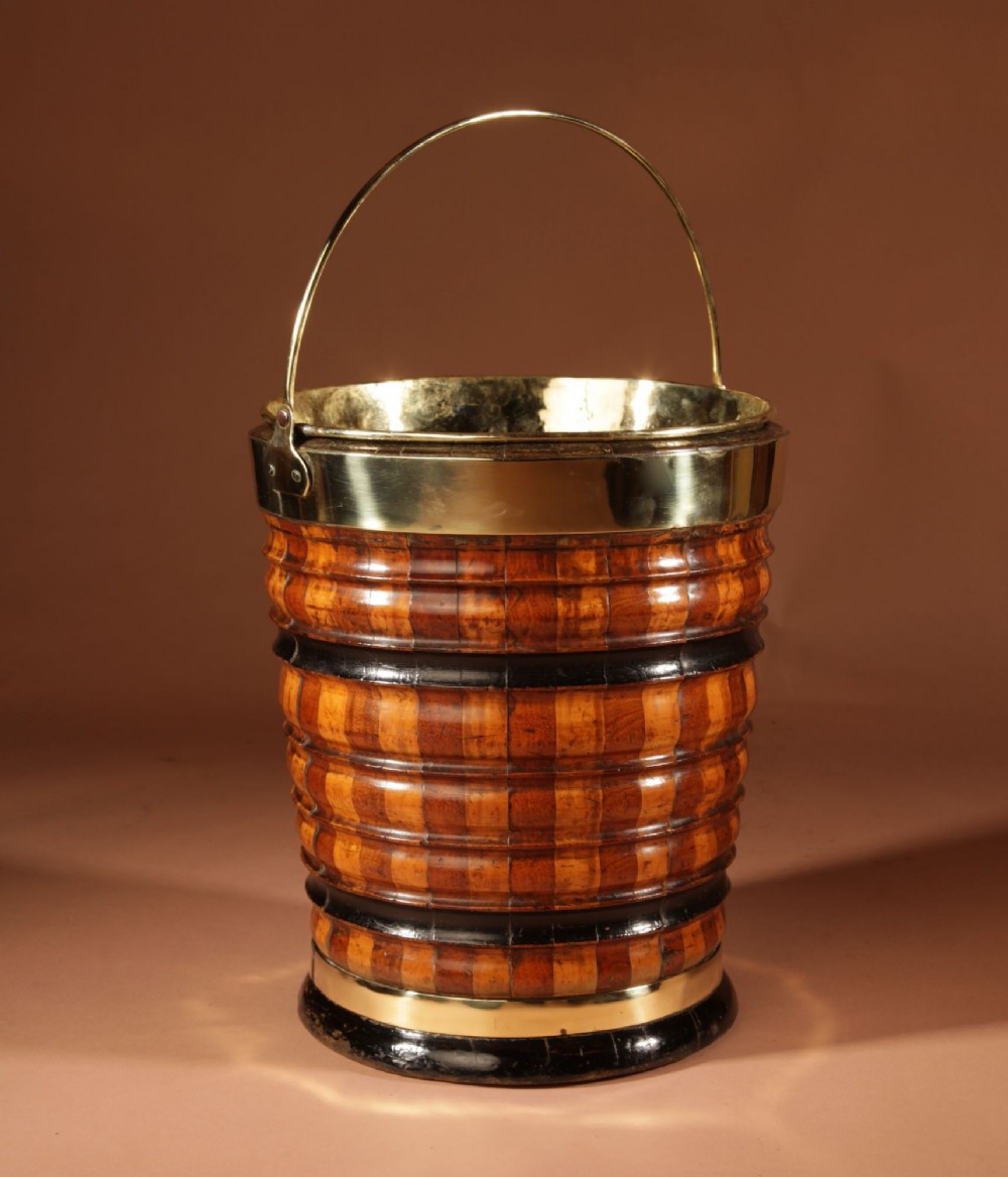 An antique coopered wooden peat bucket featuring alternating light and dark ribbed wood staves, ebonised bands, a brass rim, and a brass swing handle. View II