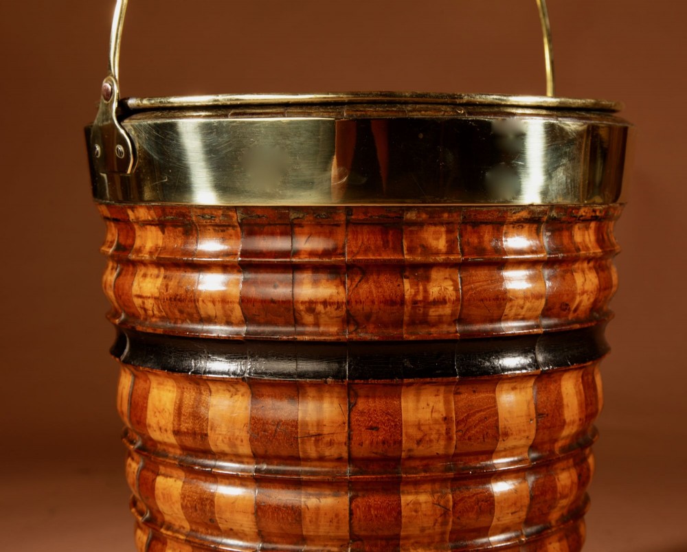 An antique coopered wooden peat bucket featuring alternating light and dark ribbed wood staves, ebonised bands, a brass rim, and a brass swing handle. View III