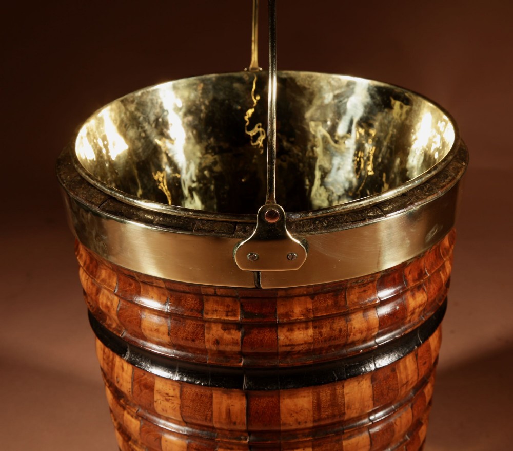 An antique coopered wooden peat bucket featuring alternating light and dark ribbed wood staves, ebonised bands, a brass rim, and a brass swing handle. View V