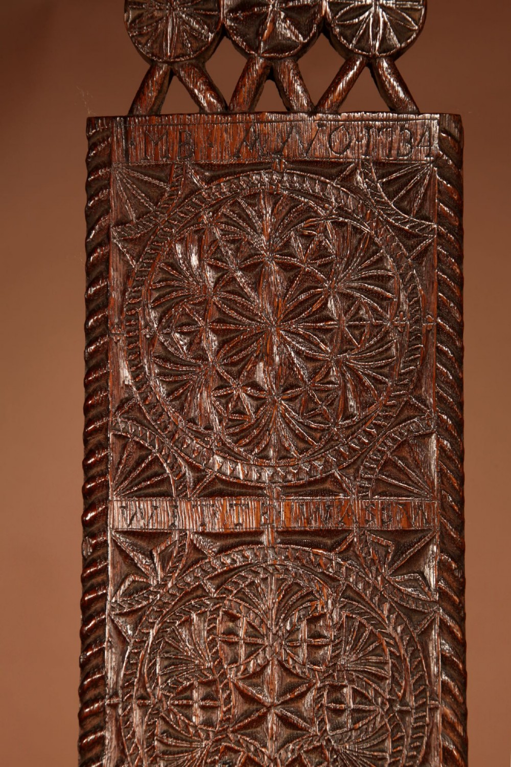 An elongated dark oak Frisian mangle board featuring intricate chip-carved geometric rosettes, carved lettering, dated 1734, and an openwork crest handle. View V