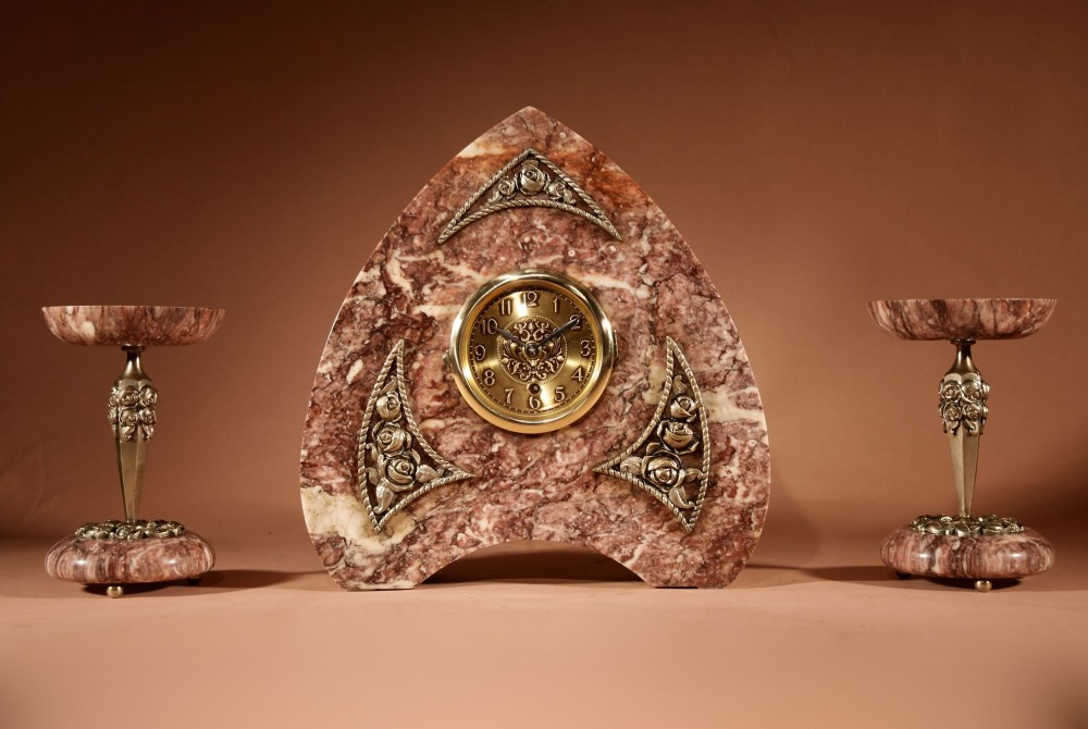 A three-piece French Art Deco clock garniture crafted from veined rose marble with brass floral embellishments and matching side tazzas. View III