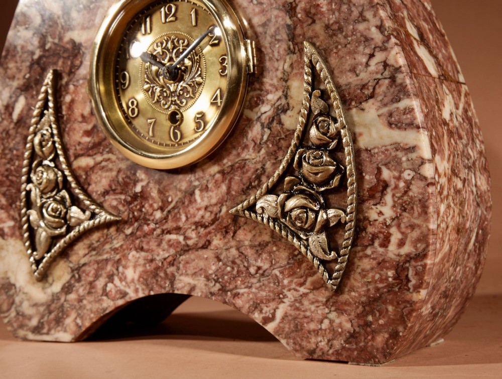 A three-piece French Art Deco clock garniture crafted from veined rose marble with brass floral embellishments and matching side tazzas. View V