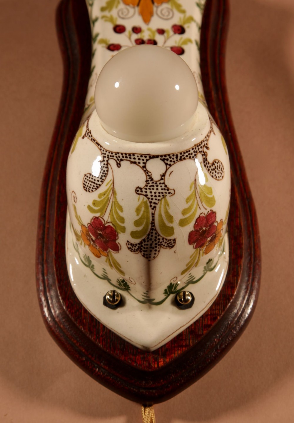 A Dutch Art Nouveau hand-painted ceramic wall sconce with floral patterns, mounted on a dark wooden backplate with an illuminated bulb. View IX