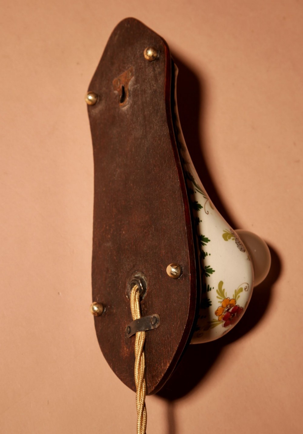A Dutch Art Nouveau hand-painted ceramic wall sconce with floral patterns, mounted on a dark wooden backplate with an illuminated bulb. View XI